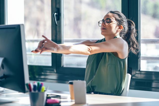 Person doing desk stretches in a modern office